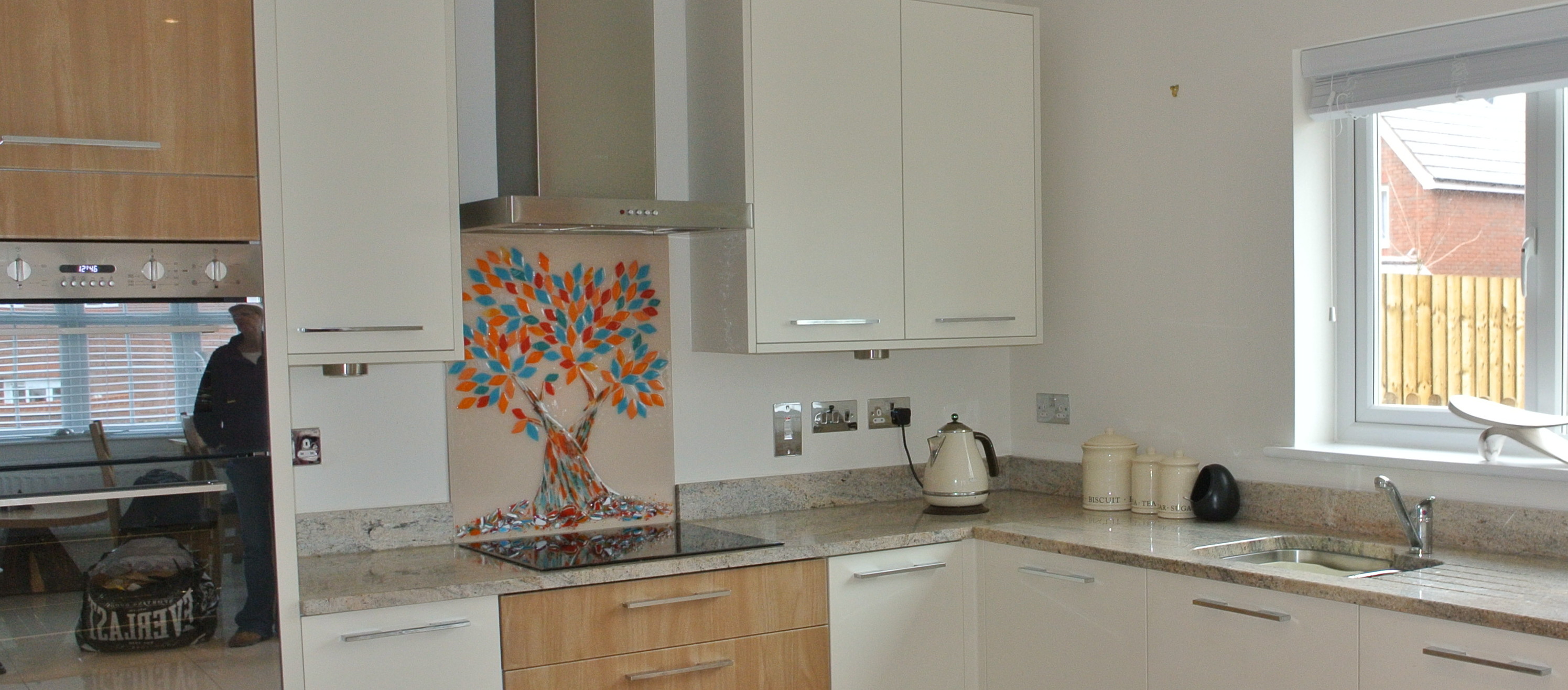 Bespoke, hand made Tree of Life glass splashback in turquoise and orange in a white kitchen